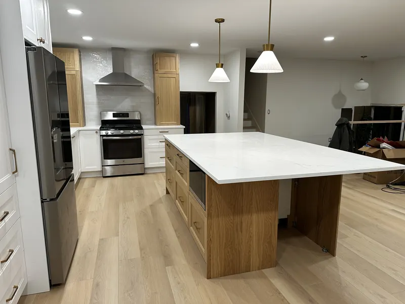 The finished open-plan kitchen with a large island, stainless appliances and new lighting
