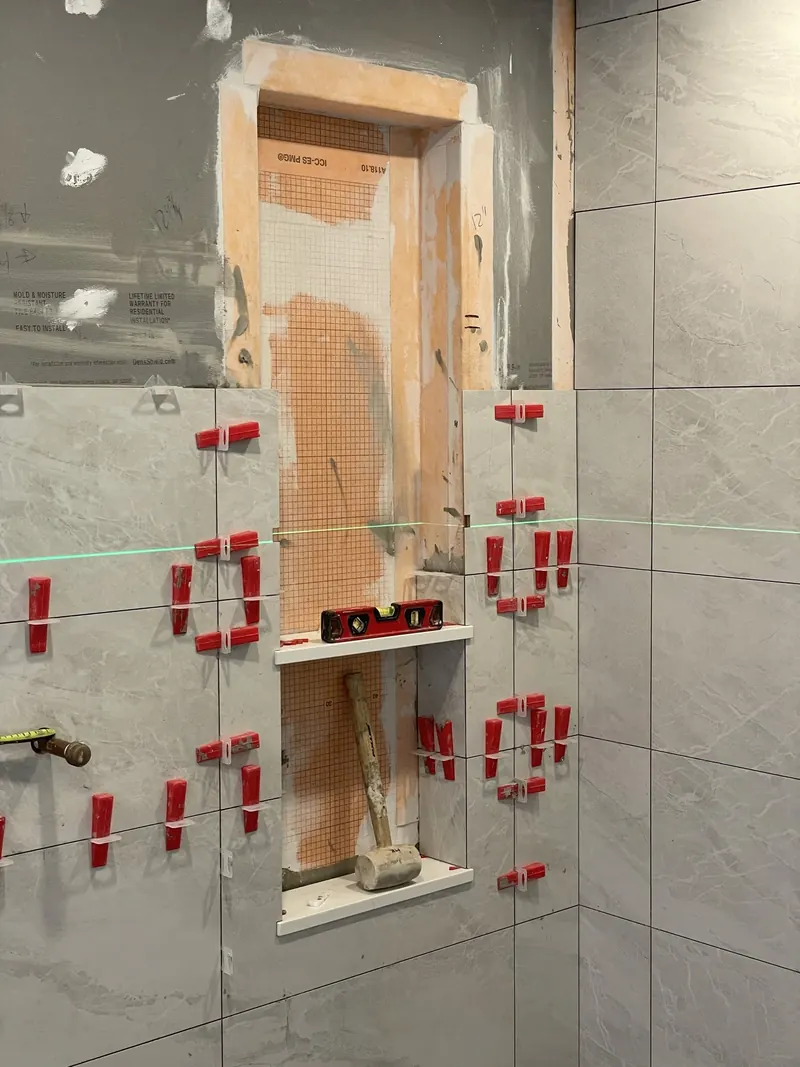 Shower niche being tiled with mitred corners and levelling clips