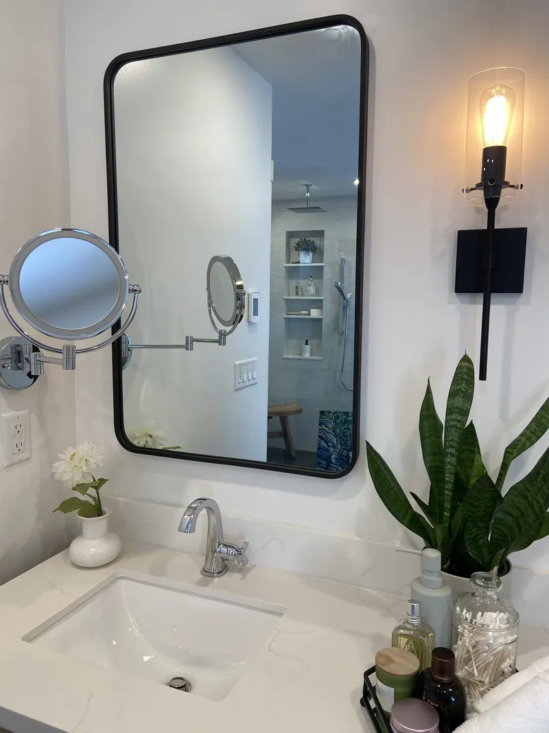 Backlit mirror and wall-mounted magnifying mirror above the vanity