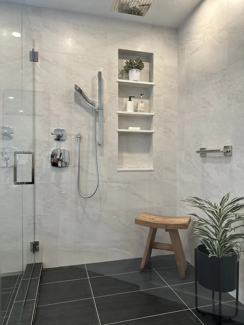 Glass encased shower with niche shelving and a teak stool